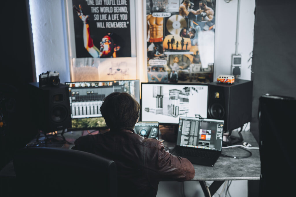 Musikproduzent bei der Arbeit im Tonstudio Gütersloh mit mehreren Monitoren, Studio-Lautsprechern und moderner Recording-Software für professionelle Musikproduktion und Mixing.